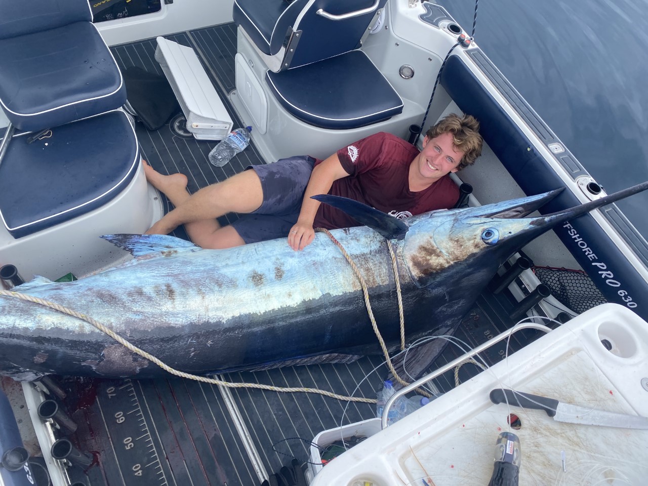 Dominic Connors beside a marlin aboard a boat